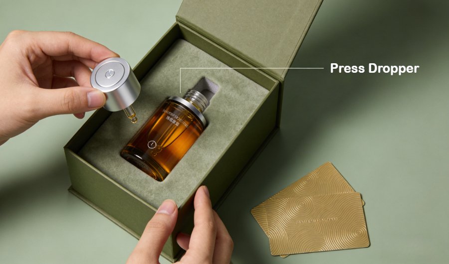 Luxury unboxing experience: matte compostable outer box with velvet lining, amber glass serum bottle with magnetic cap, textured hot-stamped product card
